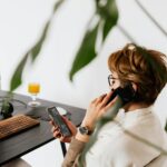busy female talking on smartphone and checking messages during work in contemporary office